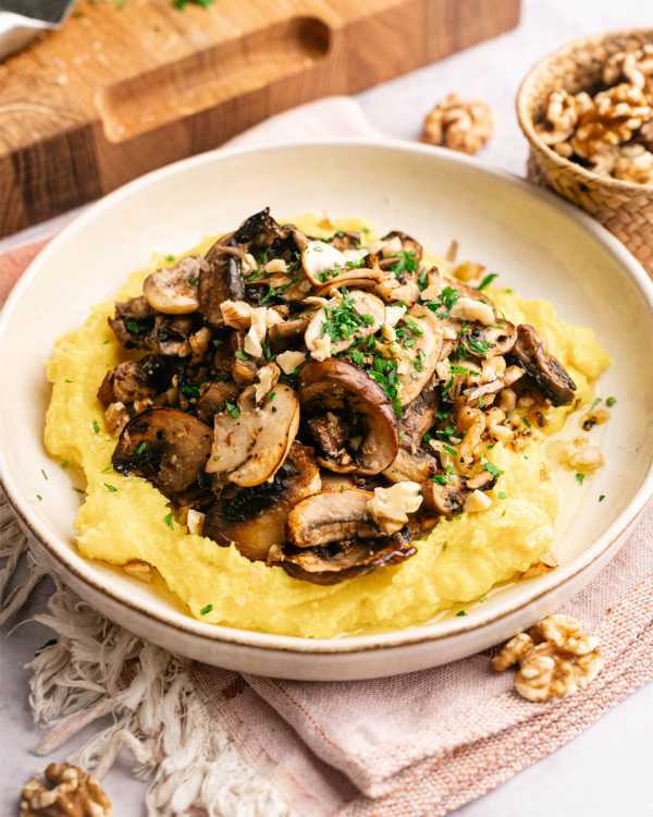 Cremige Polenta mit dunklem Pilzragout, gehackten Walnüssen und Petersilie